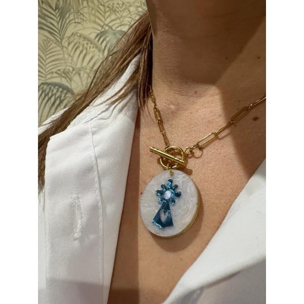 Un diseño exclusivo que une tradición y estilo actual. Esta medalla de la Virgen del Pilar, realizada en metacrilato marmoleado con efecto espejo, es perfecta para llevar a diario o regalar en una ocasión especial.