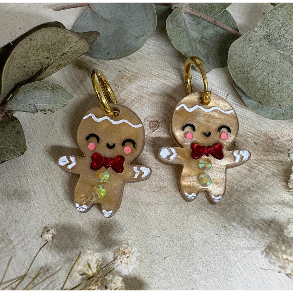 Los Pendientes Galleta de Jengibre llegan a Judithconalma para convertirse en uno de los accesorios más adorables y originales de esta Navidad. Inspirados en el icono más dulce de las fiestas, estos pendientes combinan ternura, brillo y ese toque totalmente artesanal que caracteriza nuestras colecciones navideñas. Fabricados en metacrilato de alta calidad con acabado perlado y detalles pintados a mano, cada galletita tiene un encanto único: mejillas sonrosadas, sonrisa adorable y un lazo rojo efecto espejo que aporta un toque festivo espectacular. Una pieza luminosa y superligera, diseñada para brillar en cenas, quedadas familiares, sesiones de fotos navideñas o cualquier look especial de estas fiestas.
