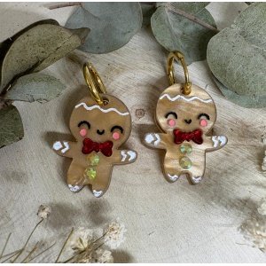Los Pendientes Galleta de Jengibre llegan a Judithconalma para convertirse en uno de los accesorios más adorables y originales de esta Navidad. Inspirados en el icono más dulce de las fiestas, estos pendientes combinan ternura, brillo y ese toque totalmente artesanal que caracteriza nuestras colecciones navideñas. Fabricados en metacrilato de alta calidad con acabado perlado y detalles pintados a mano, cada galletita tiene un encanto único: mejillas sonrosadas, sonrisa adorable y un lazo rojo efecto espejo que aporta un toque festivo espectacular. Una pieza luminosa y superligera, diseñada para brillar en cenas, quedadas familiares, sesiones de fotos navideñas o cualquier look especial de estas fiestas.