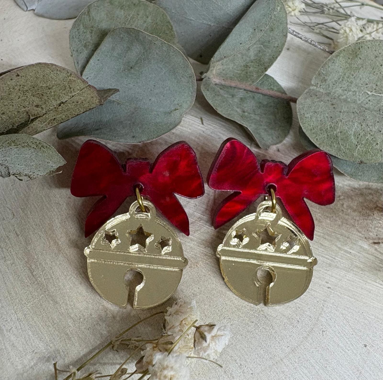 Los Pendientes Cascabel Navideño llegan para convertirse en uno de los imprescindibles de la Colección Navidad 2025 de Judithconalma. Un diseño delicado, brillante y lleno de encanto que combina dos materiales protagonistas: acrílico efecto espejo dorado en forma de pequeña campana y un lazo rojo marmoleado que aporta color, calidez y un toque muy navideño.