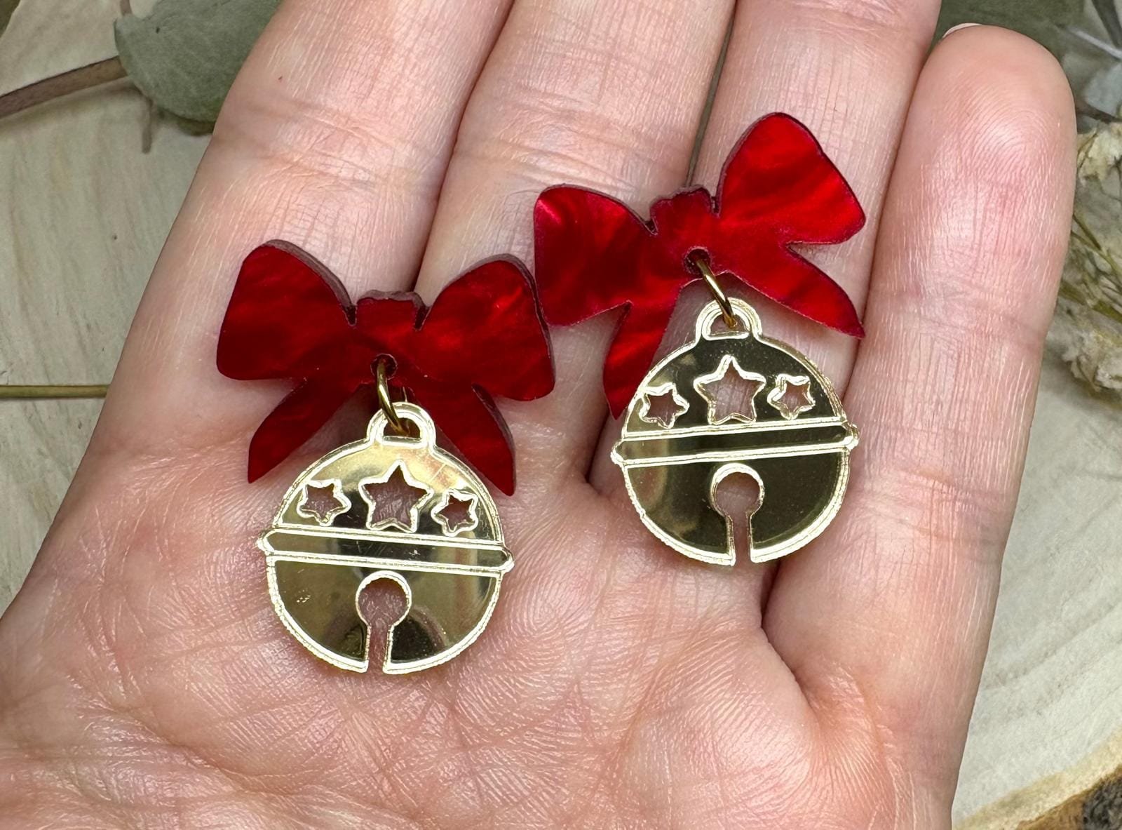 Los Pendientes Cascabel Navideño llegan para convertirse en uno de los imprescindibles de la Colección Navidad 2025 de Judithconalma. Un diseño delicado, brillante y lleno de encanto que combina dos materiales protagonistas: acrílico efecto espejo dorado en forma de pequeña campana y un lazo rojo marmoleado que aporta color, calidez y un toque muy navideño.