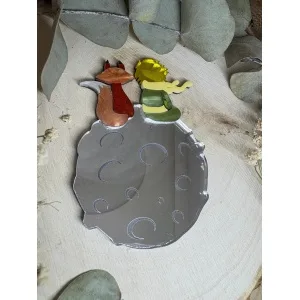 El Broche El Principito es una pieza única que combina artesanía, emoción y diseño. Inspirado en uno de los personajes más entrañables de la literatura universal, este broche está realizado a mano minuciosamente, cuidando cada detalle para crear una joya especial, delicada y llena de significado. Fabricado con metacrilatos de importación de alta calidad, incorpora acabados efecto espejo y marmoleados, que aportan profundidad, brillo y un juego de luces espectacular. Cada capa ha sido cortada con máquina láser de alta precisión, lo que permite un encaje perfecto y una definición impecable en cada forma. Su diseño representa al Principito junto a su inseparable zorro sobre su pequeño planeta, una escena que transmite ternura, amistad y magia. Gracias a la combinación de colores y materiales, el broche resulta llamativo sin perder elegancia, convirtiéndose en un complemento ideal tanto para el día a día como para ocasiones especiales.