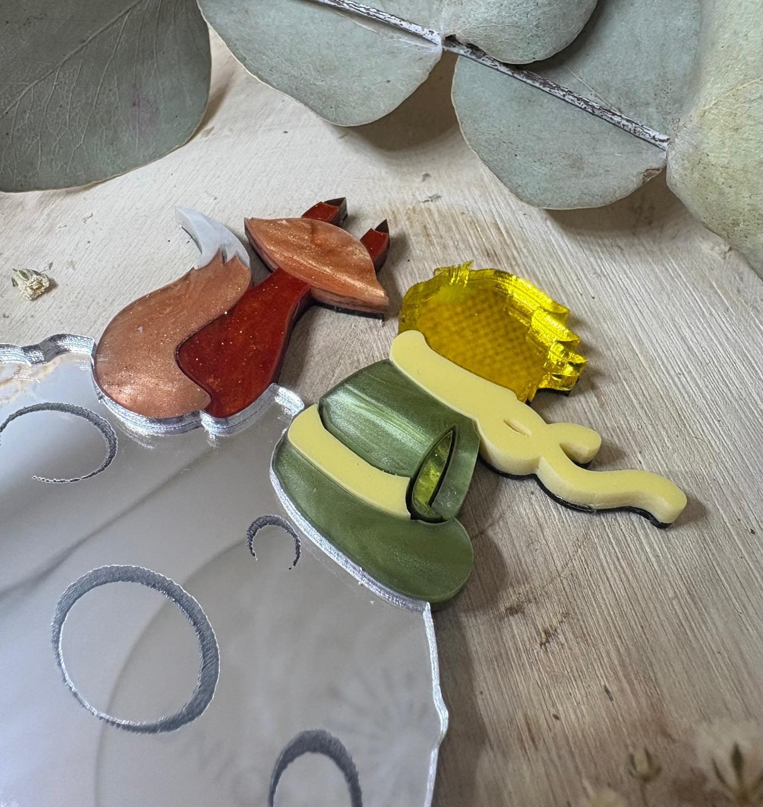 El Broche El Principito es una pieza única que combina artesanía, emoción y diseño. Inspirado en uno de los personajes más entrañables de la literatura universal, este broche está realizado a mano minuciosamente, cuidando cada detalle para crear una joya especial, delicada y llena de significado. Fabricado con metacrilatos de importación de alta calidad, incorpora acabados efecto espejo y marmoleados, que aportan profundidad, brillo y un juego de luces espectacular. Cada capa ha sido cortada con máquina láser de alta precisión, lo que permite un encaje perfecto y una definición impecable en cada forma. Su diseño representa al Principito junto a su inseparable zorro sobre su pequeño planeta, una escena que transmite ternura, amistad y magia. Gracias a la combinación de colores y materiales, el broche resulta llamativo sin perder elegancia, convirtiéndose en un complemento ideal tanto para el día a día como para ocasiones especiales.