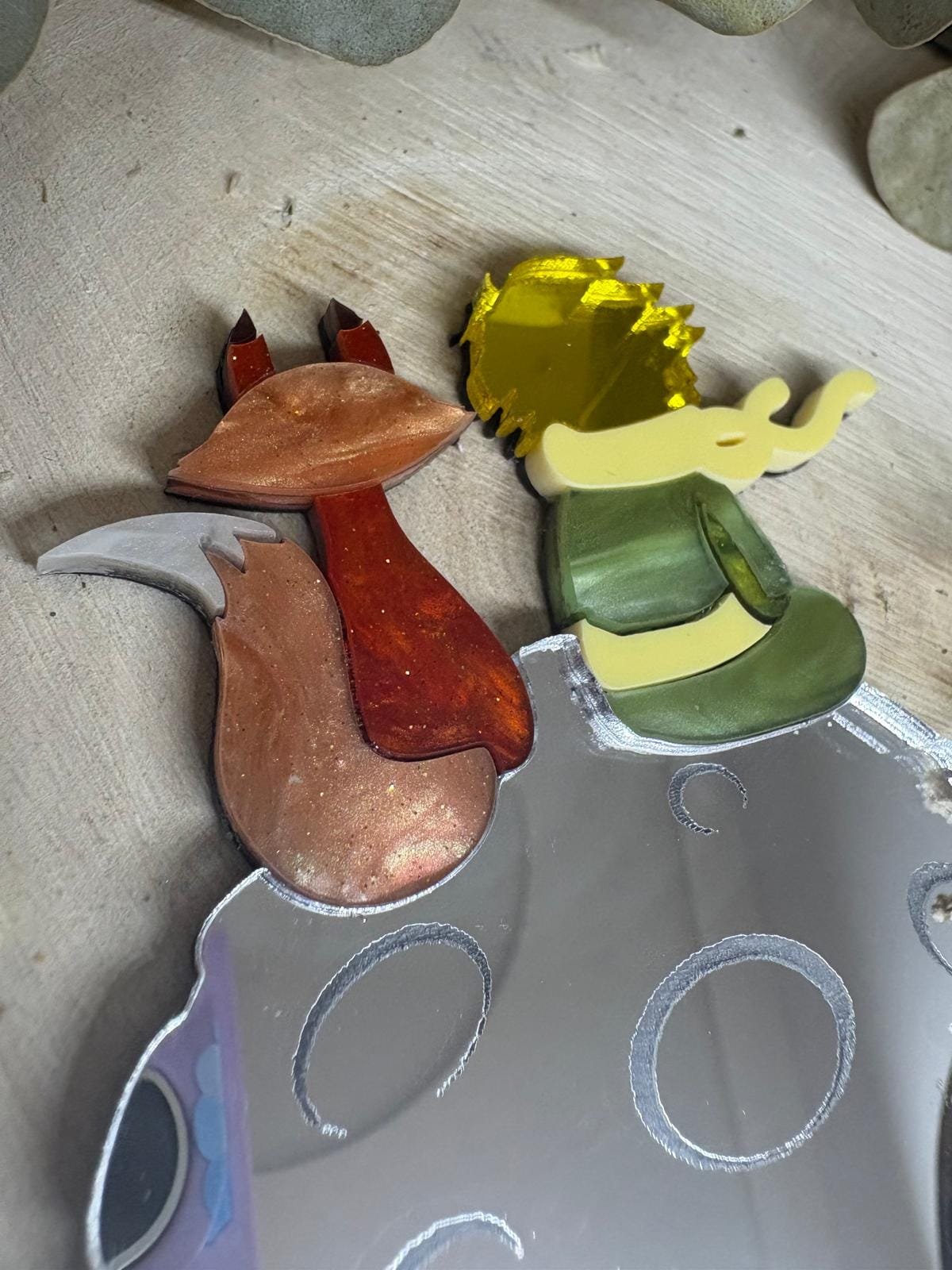 El Broche El Principito es una pieza única que combina artesanía, emoción y diseño. Inspirado en uno de los personajes más entrañables de la literatura universal, este broche está realizado a mano minuciosamente, cuidando cada detalle para crear una joya especial, delicada y llena de significado. Fabricado con metacrilatos de importación de alta calidad, incorpora acabados efecto espejo y marmoleados, que aportan profundidad, brillo y un juego de luces espectacular. Cada capa ha sido cortada con máquina láser de alta precisión, lo que permite un encaje perfecto y una definición impecable en cada forma. Su diseño representa al Principito junto a su inseparable zorro sobre su pequeño planeta, una escena que transmite ternura, amistad y magia. Gracias a la combinación de colores y materiales, el broche resulta llamativo sin perder elegancia, convirtiéndose en un complemento ideal tanto para el día a día como para ocasiones especiales.