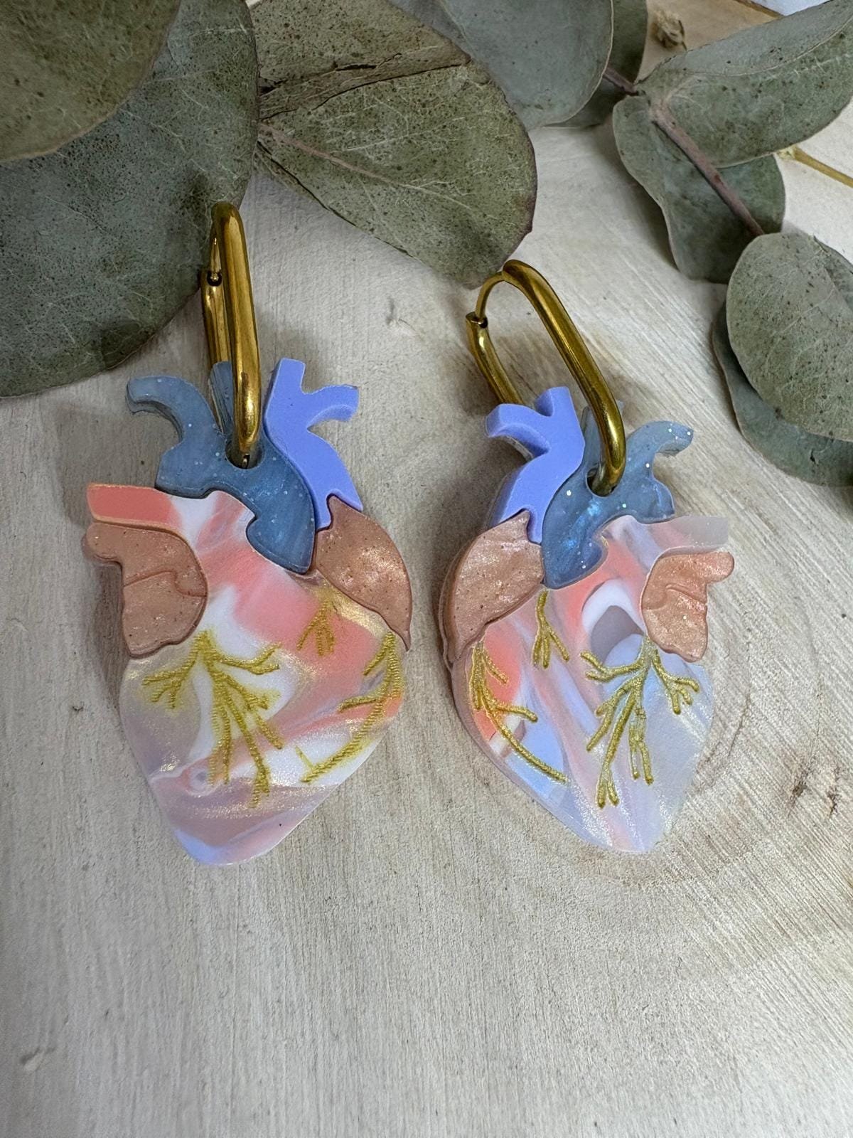 Los Pendientes Corazón Anatómico son una pieza impactante, diferente y con mucha personalidad. Un diseño exclusivo de Judithconalma, pensado para mujeres que buscan joyas originales, con fuerza visual y un significado profundo. No pasan desapercibidos: son arte, expresión y carácter en forma de pendiente. Cada corazón está inspirado en la anatomía real, reinterpretado de manera artística y contemporánea mediante una máquina láser de alta precisión, lo que permite un nivel de detalle excepcional en cada pieza. El resultado es un pendiente espectacular, moderno y muy cuidado, donde se aprecia cada forma, cada capa y cada textura.