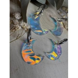 Un diseño que atrapa la luz y no pasa desapercibido. Las Lunas iridiscentes texturizadas son un modelo exclusivo de Judithconalma, creado para quienes buscan pendientes diferentes, ligeros y con un brillo especial que cambia según la luz y el movimiento. Cada luna está realizada en metacrilato iridiscente de última generación, con una textura sutil que aporta profundidad y reflejos únicos en tonos nacarados, azules, rosados y dorados. No hay dos iguales: cada pieza tiene su propio juego de luces. Diseño exclusivo y hecho a mano