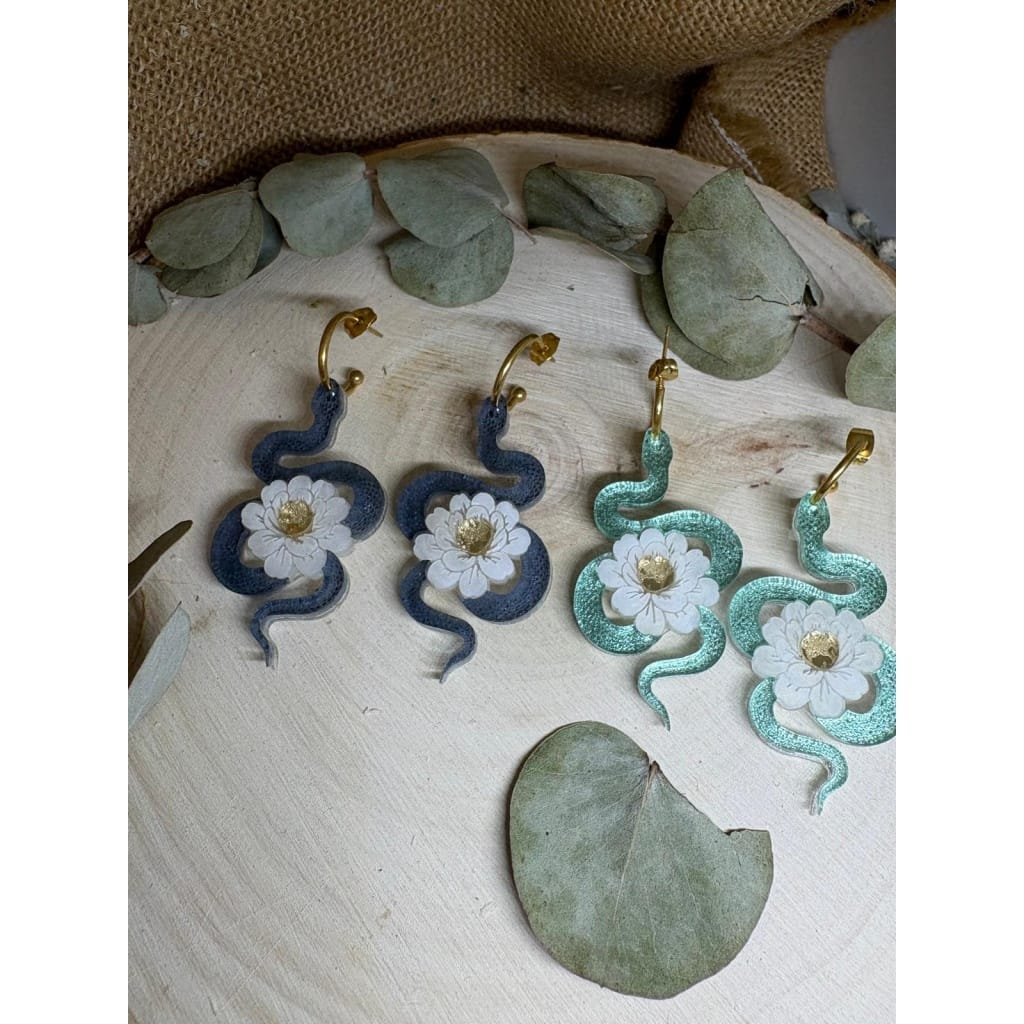 Un diseño con carácter, simbolismo y elegancia. Los Pendientes Serpiente Metacrilato son un modelo exclusivo de Judithconalma que une fuerza y delicadeza en una misma pieza. La serpiente, símbolo de transformación y poder, se combina con una flor marmoleada luminosa que aporta equilibrio, luz y feminidad. Un contraste que convierte este diseño en algo verdaderamente especial.