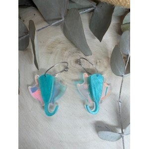 Pendientes Manta Raya – Colección Verano 2026 Los Pendientes Manta Raya de Judith con Alma son una pieza original y elegante inspirada en la belleza y la libertad del océano. Su diseño exclusivo reproduce la silueta de una manta raya en movimiento, creando unos pendientes únicos que evocan el mar, el verano y los días de playa. Fabricados artesanalmente con metacrilatos de importación de alta calidad, combinan un espectacular tono turquesa marmoleado con un metacrilato iridiscente que refleja diferentes colores según la luz. El resultado es una joya ligera, llamativa y llena de personalidad que no pasa desapercibida. Cada pendiente está cortado con tecnología láser de alta precisión, consiguiendo acabados limpios y detalles perfectamente definidos. Su tamaño de 3 x 3 cm (sin aro) los convierte en un complemento cómodo y versátil para el día a día, mientras que el aro fino plateado de 2 cm aporta un toque moderno y elegante. Estos pendientes forman parte de la exclusiva Colección Verano 2026 de Judith con Alma, una colección inspirada en el mar, la costa y la naturaleza marina. Son ideales para completar un look veraniego, para tus vacaciones, una cena junto al mar o simplemente para aportar frescura y originalidad a cualquier conjunto. Si buscas pendientes originales de metacrilato, pendientes inspirados en el mar o complementos artesanales diferentes, los Pendientes Manta Raya son la elección perfecta. Características principales Diseño exclusivo Judith con Alma. Inspirados en las mantas raya y el mundo marino. Fabricados con metacrilatos de importación de alta calidad. Combinación de metacrilato turquesa y efecto iridiscente. Corte láser de alta precisión. Muy ligeros y cómodos de llevar. Medida de la figura: 3 x 3 cm. Aro fino plateado de 2 cm. Ideales para looks de verano. Pieza artesanal realizada en pequeñas series. Colección Verano 2026.