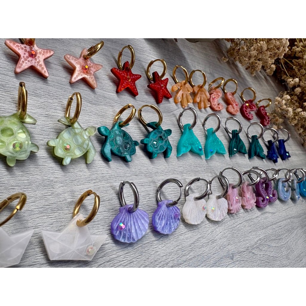 Descubre TESOROS DEL MAR, la colección más divertida y personalizable del verano. Pendientes inspirados en el océano para crear combinaciones únicas, llenas de color, brillo y personalidad. Elige tus figuras favoritas, mezcla colores y crea un diseño totalmente a tu gusto. Características: Diseño exclusivo de JudithconAlma Modelos disponibles: concha, coral, estrella de mar, ballena, tortuga, ola, cola de ballena, barco de papel, tentáculos, sepia y gambitas Tamaño aproximado: 1,7 x 1,7 cm Posibilidad de elegir pendientes iguales o diferentes Personalizables en color y combinación Opción con aro o sin aro Aro disponible en color dorado o plateado Aros de acero inoxidable aptos para alergias Ligeros y muy cómodos de llevar Perfectos para looks veraniegos, coloridos y desenfadados Ideales para playa, vacaciones, festivales y verano Cada combinación es única y hecha con mucho mimo