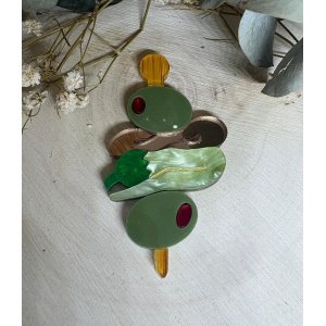 Descubre una pieza única que combina creatividad, tradición y mucho estilo: el BROCHE GILDA DE METACRILATO, un diseño exclusivo que no pasa desapercibido. Inspirado en uno de los aperitivos más icónicos, este broche reinterpreta la clásica gilda con un toque moderno, artístico y lleno de personalidad. Perfecto para quienes buscan accesorios originales que marquen la diferencia, este broche es mucho más que un complemento: es una declaración de estilo. Elaborado con metacrilatos de alta calidad y trabajados con precisión, cada detalle ha sido cuidadosamente diseñado para recrear la esencia de la gilda de una forma elegante y divertida. La combinación de distintos acabados —efecto madera, marmoleado, espejo y liso— aporta profundidad, textura y un juego visual muy atractivo que capta la luz y las miradas. Además, los tonos verdes y detalles en rojo evocan fielmente los ingredientes tradicionales, creando una pieza reconocible pero con un aire contemporáneo. Gracias a su tamaño de 6,5 x 4 cm, este broche tiene la presencia ideal para destacar en chaquetas, blazers, bolsos o incluso prendas más informales, aportando un toque desenfadado y sofisticado al mismo tiempo. Es ligero y cómodo de llevar durante todo el día, lo que lo convierte en el aliado perfecto tanto para looks diarios como para ocasiones especiales. Este modelo exclusivo de JudithconAlma está pensado para quienes valoran la originalidad, el diseño artesanal y los pequeños detalles que marcan la diferencia. Cada broche es único, reflejando el cuidado y la dedicación en su creación. Si te apasionan los accesorios diferentes, con carácter y un guiño a la cultura gastronómica, el BROCHE GILDA DE METACRILATO es una elección que no puede faltar en tu colección. Dale a tus outfits un toque creativo, divertido y absolutamente inolvidable.