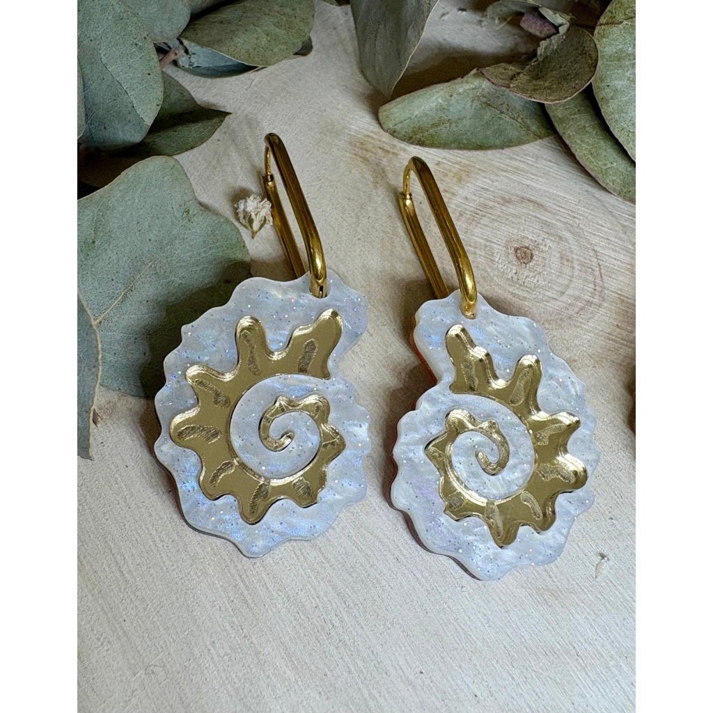 Pendientes Caracola de Metacrilato – Diseño Elegante y Original Los Pendientes Caracola son una auténtica joyita inspirada en el mar y en las formas orgánicas de la naturaleza. Un diseño original y sofisticado que combina diferentes metacrilatos para crear un efecto visual espectacular, lleno de brillo, textura y personalidad. Su forma de caracola aporta un estilo elegante pero diferente, perfecto para quienes buscan unos pendientes de metacrilato originales, ligeros y con mucho encanto. La mezcla de acabados nacarados, efecto brillo y espejo dorado convierte cada pieza en un complemento único y muy favorecedor. Además, puedes elegir entre dos tipos de aro para adaptarlos totalmente a tu estilo: aro ovalado o aro redondo. ✨ Características principales 🐚 Diseño exclusivo inspirado en caracolas marinas 🎨 Combinación de varios metacrilatos de alta calidad ✂️ Corte láser de precisión 💎 Acabados nacarados, brillo y efecto espejo 📏 Medidas: 3,5 x 2,4 cm (sin aro) 🔘 Opciones de aro: Ovalado: 2 cm x 1,5 cm Redondo: 1,8 cm 🪶 Muy ligeros y cómodos ✋ Hechos a mano con muchísimo mimo 🌊 Diseño elegante, original y muy veraniego Perfectos para elevar cualquier look y aportar un toque especial tanto en el día a día como en ocasiones especiales. Si te encantan los complementos diferentes y con personalidad, estos pendientes están hechos para ti.