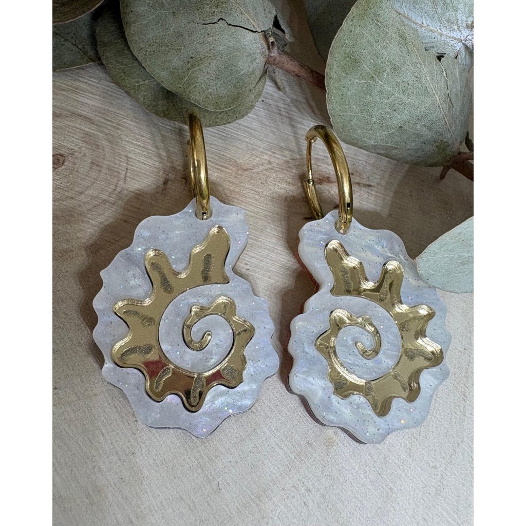 Pendientes Caracola de Metacrilato – Diseño Elegante y Original Los Pendientes Caracola son una auténtica joyita inspirada en el mar y en las formas orgánicas de la naturaleza. Un diseño original y sofisticado que combina diferentes metacrilatos para crear un efecto visual espectacular, lleno de brillo, textura y personalidad. Su forma de caracola aporta un estilo elegante pero diferente, perfecto para quienes buscan unos pendientes de metacrilato originales, ligeros y con mucho encanto. La mezcla de acabados nacarados, efecto brillo y espejo dorado convierte cada pieza en un complemento único y muy favorecedor. Además, puedes elegir entre dos tipos de aro para adaptarlos totalmente a tu estilo: aro ovalado o aro redondo. ✨ Características principales 🐚 Diseño exclusivo inspirado en caracolas marinas 🎨 Combinación de varios metacrilatos de alta calidad ✂️ Corte láser de precisión 💎 Acabados nacarados, brillo y efecto espejo 📏 Medidas: 3,5 x 2,4 cm (sin aro) 🔘 Opciones de aro: Ovalado: 2 cm x 1,5 cm Redondo: 1,8 cm 🪶 Muy ligeros y cómodos ✋ Hechos a mano con muchísimo mimo 🌊 Diseño elegante, original y muy veraniego Perfectos para elevar cualquier look y aportar un toque especial tanto en el día a día como en ocasiones especiales. Si te encantan los complementos diferentes y con personalidad, estos pendientes están hechos para ti.