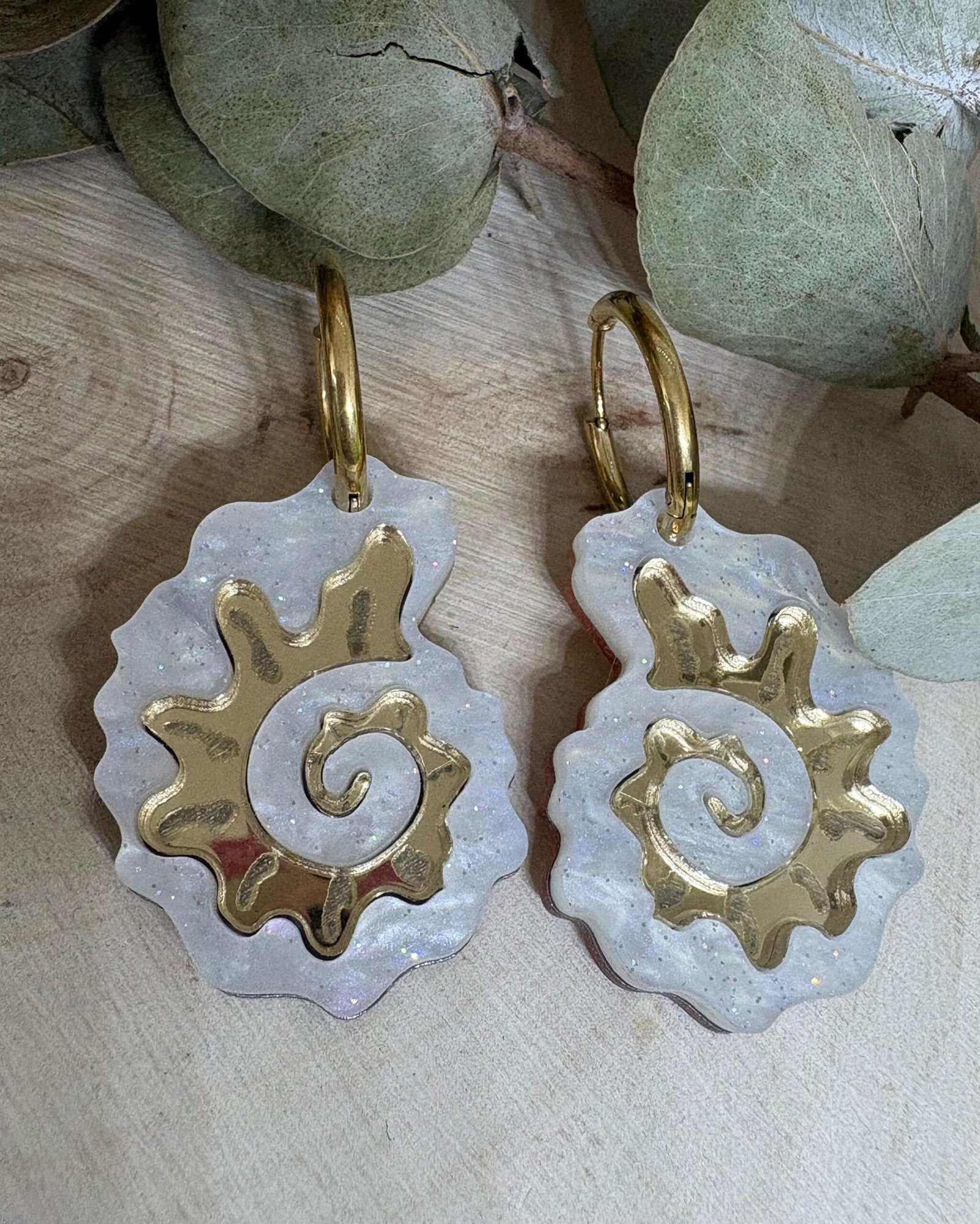 Pendientes Caracola de Metacrilato – Diseño Elegante y Original Los Pendientes Caracola son una auténtica joyita inspirada en el mar y en las formas orgánicas de la naturaleza. Un diseño original y sofisticado que combina diferentes metacrilatos para crear un efecto visual espectacular, lleno de brillo, textura y personalidad. Su forma de caracola aporta un estilo elegante pero diferente, perfecto para quienes buscan unos pendientes de metacrilato originales, ligeros y con mucho encanto. La mezcla de acabados nacarados, efecto brillo y espejo dorado convierte cada pieza en un complemento único y muy favorecedor. Además, puedes elegir entre dos tipos de aro para adaptarlos totalmente a tu estilo: aro ovalado o aro redondo. ✨ Características principales 🐚 Diseño exclusivo inspirado en caracolas marinas 🎨 Combinación de varios metacrilatos de alta calidad ✂️ Corte láser de precisión 💎 Acabados nacarados, brillo y efecto espejo 📏 Medidas: 3,5 x 2,4 cm (sin aro) 🔘 Opciones de aro: Ovalado: 2 cm x 1,5 cm Redondo: 1,8 cm 🪶 Muy ligeros y cómodos ✋ Hechos a mano con muchísimo mimo 🌊 Diseño elegante, original y muy veraniego Perfectos para elevar cualquier look y aportar un toque especial tanto en el día a día como en ocasiones especiales. Si te encantan los complementos diferentes y con personalidad, estos pendientes están hechos para ti.