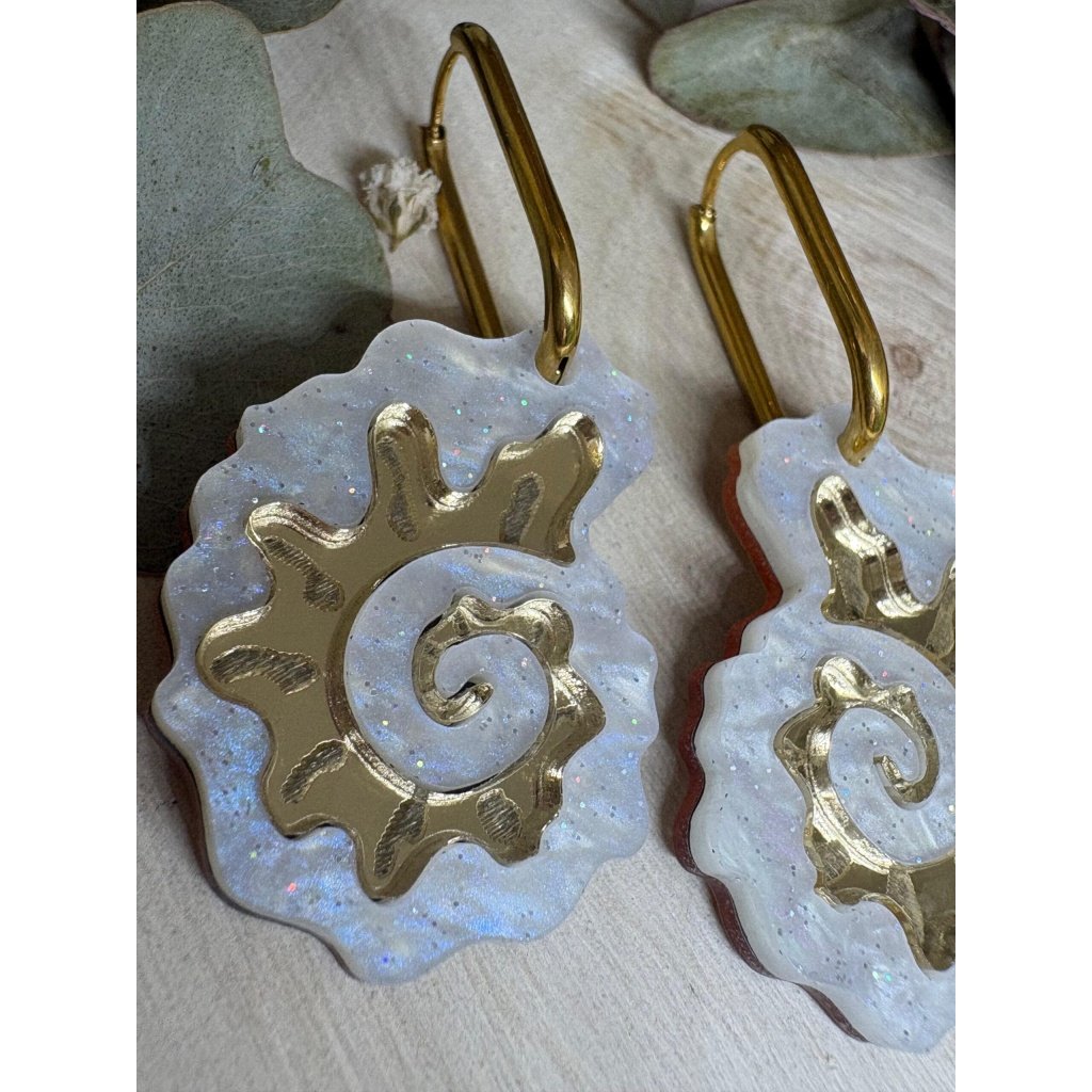 Pendientes Caracola de Metacrilato – Diseño Elegante y Original Los Pendientes Caracola son una auténtica joyita inspirada en el mar y en las formas orgánicas de la naturaleza. Un diseño original y sofisticado que combina diferentes metacrilatos para crear un efecto visual espectacular, lleno de brillo, textura y personalidad. Su forma de caracola aporta un estilo elegante pero diferente, perfecto para quienes buscan unos pendientes de metacrilato originales, ligeros y con mucho encanto. La mezcla de acabados nacarados, efecto brillo y espejo dorado convierte cada pieza en un complemento único y muy favorecedor. Además, puedes elegir entre dos tipos de aro para adaptarlos totalmente a tu estilo: aro ovalado o aro redondo. ✨ Características principales 🐚 Diseño exclusivo inspirado en caracolas marinas 🎨 Combinación de varios metacrilatos de alta calidad ✂️ Corte láser de precisión 💎 Acabados nacarados, brillo y efecto espejo 📏 Medidas: 3,5 x 2,4 cm (sin aro) 🔘 Opciones de aro: Ovalado: 2 cm x 1,5 cm Redondo: 1,8 cm 🪶 Muy ligeros y cómodos ✋ Hechos a mano con muchísimo mimo 🌊 Diseño elegante, original y muy veraniego Perfectos para elevar cualquier look y aportar un toque especial tanto en el día a día como en ocasiones especiales. Si te encantan los complementos diferentes y con personalidad, estos pendientes están hechos para ti.