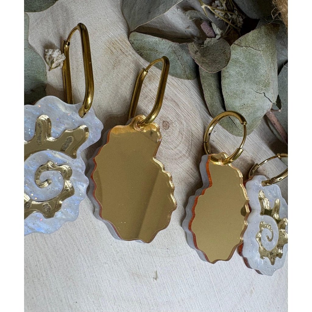 Pendientes Caracola de Metacrilato – Diseño Elegante y Original Los Pendientes Caracola son una auténtica joyita inspirada en el mar y en las formas orgánicas de la naturaleza. Un diseño original y sofisticado que combina diferentes metacrilatos para crear un efecto visual espectacular, lleno de brillo, textura y personalidad. Su forma de caracola aporta un estilo elegante pero diferente, perfecto para quienes buscan unos pendientes de metacrilato originales, ligeros y con mucho encanto. La mezcla de acabados nacarados, efecto brillo y espejo dorado convierte cada pieza en un complemento único y muy favorecedor. Además, puedes elegir entre dos tipos de aro para adaptarlos totalmente a tu estilo: aro ovalado o aro redondo. ✨ Características principales 🐚 Diseño exclusivo inspirado en caracolas marinas 🎨 Combinación de varios metacrilatos de alta calidad ✂️ Corte láser de precisión 💎 Acabados nacarados, brillo y efecto espejo 📏 Medidas: 3,5 x 2,4 cm (sin aro) 🔘 Opciones de aro: Ovalado: 2 cm x 1,5 cm Redondo: 1,8 cm 🪶 Muy ligeros y cómodos ✋ Hechos a mano con muchísimo mimo 🌊 Diseño elegante, original y muy veraniego Perfectos para elevar cualquier look y aportar un toque especial tanto en el día a día como en ocasiones especiales. Si te encantan los complementos diferentes y con personalidad, estos pendientes están hechos para ti.