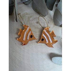 Los Pendientes Pez Mariposa de Judith con Alma son una pieza original, sofisticada y vibrante, inspirada en la exótica belleza y el colorido de los arrecifes de coral. Su diseño exclusivo evoca de forma instantánea la frescura del mar, la brisa del verano y los días eternos de playa, convirtiéndose en el accesorio imprescindible para iluminar tus mejores momentos de la nueva Colección Verano 2026. Cada una de estas piezas está meticulosamente fabricada utilizando metacrilatos de importación de la más alta calidad, combinando un deslumbrante acabado efecto espejo dorado con texturas anaranjadas y blancas que recrean las icónicas rayas del pez mariposa. Mediante un proceso de corte láser de alta precisión, logramos unos acabados impecables, limpios y llenos de luz. Además, la pieza sorprende por su doble juego visual: un lado lleno de texturas y detalles contrastados, y un reverso pulido en un espejo dorado espectacular que atrapa todos los reflejos del sol. A pesar de su gran impacto visual y sus ricos detalles, son unos pendientes extraordinariamente ligeros y cómodos de llevar, pensados para acompañarte desde una tarde en la playa hasta una cena especial en las noches de verano. Características principales Diseño exclusivo de Judith con Alma. Inspirados en el mundo marino y la fauna exótica de los océanos. Fabricados con metacrilatos de importación de alta gama. Combinación única de metacrilato efecto espejo y destellos dorados. Corte láser de alta precisión para unos acabados limpios y profesionales. Muy ligeros y cómodos, ideales para llevar durante horas. Medida de la figura: 2,6 x 2,5 cm. Aro fino dorado de 2 cm, a juego con la calidez del diseño. El complemento perfecto para resaltar tus looks de verano. Pieza artesanal realizada con mucho mimo en pequeñas series limitadas. Perteneciente a la Colección Verano 2026.