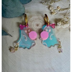 Pendientes Fantasmas Golosas  ¡Dale un toque dulce, divertido y único a tu look de Halloween con los nuevos Pendientes Fantasmas Golosas de Judith con Alma! Pertenecientes a nuestra exclusiva Colección Halloween 2026, estos pendientes combinan el encanto tenebroso de la temporada con un estilo super coqueto y femenino (coquette / sweet halloween). Cada pieza cuenta con un simpático fantasmita translúcido con destellos iridiscentes que hacen una pompa de chicle rosa, rematado con un bonito lazo en la parte superior y un delicado colgante de cristal en la base que le aporta un brillo mágico en cada movimiento. Pendientes Fantasmas Golosas – Colección Halloween 2026 Características del Producto: Medidas : 3x2,3 (sin aro) . Lleva aros de 1,5 cm Diseño 100% Exclusivo: Creación propia pensada y diseñada desde cero para que luzcas una joya original y llena de personalidad en estas Fiestas de Halloween. Metacrilatos de Importación de Alta Calidad: Metacrilato traslúcido, metacrilato espejo y opaco y piedra de cristal de máxima calidad, que reflejan tonos violetas, turquesas y anaranjados según la luz. Corte Láser de Alta Precisión: Bordes pulidos y acabados limpios que garantizan la máxima nitidez en cada detalle. Cierre Cómodo y Seguro: Aros dorados antialérgicos, ligeros y perfectos para llevar durante todo el día o noche sin molestias.